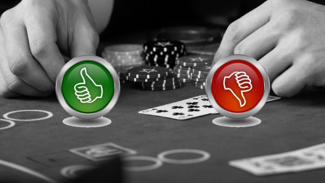 Thumbs up and thumbs down with a black and white background of hands on a poker table